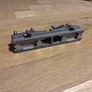 Kovový most na hudební nástroj v šedé barvě. Na boku je vyražen nápis YAMAHA s doprovodným logem. Povrch vykazuje známky používání a mírné opotřebení.