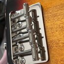 Detailní pohled na chromovaný kobylkový mechanismus s pružinami namontovaný na dřevěné ploše nástroje. Kovové součástky mají stříbrnou barvu a vykazu…