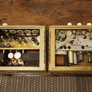 Dvě otevřené šasi staršího audio zařízení v béžovém kovovém provedení. Levá část obsahuje elektronické komponenty, vakuumové elektrony a transformáto…