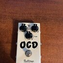 Bílý efekt pedál s nápisem OCD a značkou Fulltone Built in the USA. Zařízení má tři černé ovládací knoflíky s popisky Volume, HP/LP a Tone. Povrch je…