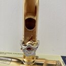 Zlatý saxofonový mouthpiece s nasazeným stříbrným ligaturem. Na spodní části mouthpiecu je vyryto "TRUE LARGE CHAMBER" a "made in USA", u ligaturem j…