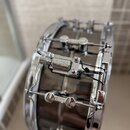 Detailní pohled na černý buben s chromovaným obručováním a kování. Na chromovaném mechanismu je vyryt nápis SONOR. Povrch nástroje je glossy, v chrom…