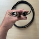 Fotografie zachycuje oba konce černého kabelu s konektory typu XLR. Jeden konektor je samice a druhý samec, oba mají kovové tělo. Kabel je svinutý do…
