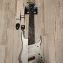 Stříbrná elektrická kytara s dvojsečným výřezem korpusu a šesti strunami. Na hlavě je viditelný nápis Ibanez. Kytara má dva humbuckery, zlatý most a…
