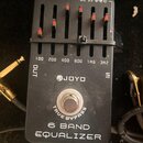 Černý kytarový pedál s nápisem JOYO a označením 6 BAND EQUALIZER. Obsahuje šest posuvníků s červenými knoflíky a popisy frekvencí 100, 200, 400, 800,…