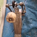 Kovový pedál basového bubnu stříbrné barvy s řetězovým pohonem. Na bočném rámu je viditelně logo Pearl. Beater je vyroben z bílého plstnatého materiá…