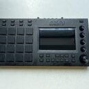 Černý sampler značky AKAI PROFESSIONAL s mřížkou 16 gumových padů a displejem. Na horní hraně jsou umístěny konektory pro MIDI, sluchátka a napájení.…