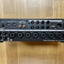Černý rackový audio rozhraní s řadou vstupů a výstupů. Na předním panelu jsou nápisy DC IN, OUT, IN, COAXIAL OUT (9/10), COAXIAL IN (15/16), LINE OUT…