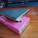 Růžový wah-wah pedál s černým gumovým nášlapem a chromovaným okrajem. Na pravém boku je viditelný nápis „George Dennis“ a pod ním menší text „CUSTOM…