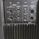 Záběr na zadní ovládací panel černého zesilovače s chladicími žebry. Panel obsahuje vstupy a výstupy typu XLR s popisky THRU (FULL RANGE OUTPUT), FUL…