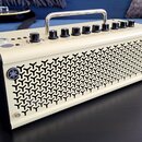 Kytarový kombozesilovač krémové barvy s kovovou rukojetí nahoře. Na předním panelu jsou ovládací knoflíky a nápisy GAIN, MASTER, REVERB. Přední mřížk…