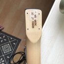 Detail hlavy kytary z přírodního světlého dřeva. Na povrchu je svisle vyryt nápis WD MUSIC LC BY FENDER. V horní části jsou vidět čtyři otvory pro la…