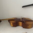 Dřevěné smyčcové nástroje typu violoncello v hnědém lakovaném provedení. Nástroj leží na boku, jsou vidět struny a kobylka. Na povrchu nejsou patrné…