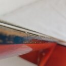 Detailní pohled na hranu hmatníku a krku kytary. Povrch dřeva v místě spojení s červeným lakovaným tělem vykazuje výrazné opotřebení, odřeniny a chyb…