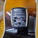 Detailní pohled na elektronický preamp zabudovaný v těle akustické kytary s žlutohnatým povrchem. Na panelu je nápis Esonic 2 a značka Shadow, dále o…