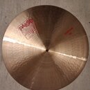 Kruhový mosazný činel s jemným rýhováním a kovaným povrchem. Na povrchu je červený nápis PAISTE 2002 s doplňky TRADE MARK MADE IN SWITZERLAND a červe…