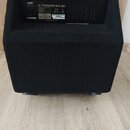 Zadní strana černého basového komba potaženého texturovaným materiálem. Na zadním panelu je nápis ULTRABASS BHL450, logo RoHS a značka CE. Jsou zde r…
