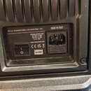 Detail zadní strany černého elektronického zařízení s plastovým povrchem. Je zde vidět napájecí vstup, vypínač a štitek s nápisy: RCF S.p.A. VIA RAFF…