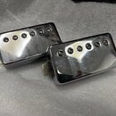 Dvě elektrické kytarové snímače typu humbucker s chromovaným kovovým krytem. Každý snímač má na povrchu šest viditelných polótek. Povrch krytů vykazu…