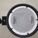 Elektronický bicí pad s bílou síťovou membránou v černém kruhovém rámu. Na membráně jsou nápisy Roland, MESH HEAD, Reg. U.S. Pat. & Tm. Off. a V-Drum…