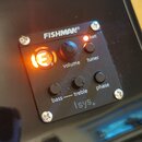 Černý ovládací panel s nápisem FISHMAN® a označením Isys+. Panel obsahuje otočný ovladač volume, dva menší ovladače bass a treble spojené čarou, tlač…