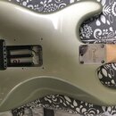 Zadní strana elektrické kytary v odstínu stříbrno-zelené metalik. Na kovém spojovacím plechu u krku je nápis Fender CORONA CALIFORNIA. V dolní části…