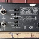 Záběr na zadní panel černého elektronického zařízení s konektory a přepínači. Jsou zde viditelné nápisy GROUND, MODE, LIMITER, SENSITIVITY a FILTER s…