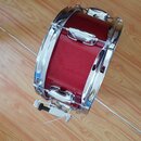 Červený snare drum s chromovaným obručováním a kováním. Povrch korpusu má jemnou kovovou texturu. Na nástroji není vidět žádná značka ani modelové oz…