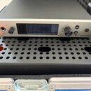 Stříbrný elektronický přístroj značky SENNHEISER s označením ew G4. Na předním panelu je displej, dva ovratové ovladače, konektor pro sluchátka s iko…