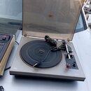 Gramofon v šedém provedení s otevřeným průhledným plastovým krytem. Na levé straně šasi je nápis TESLA a na pravé straně nápis NC 300. Přístroj obsah…
