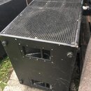 Černý reproduktorový box s kovovou mřížkou na horní straně. Na boční stěně jsou umístěny dvě obdélníkové úchopky s madly a čtyři gumové nožičky. Povr…