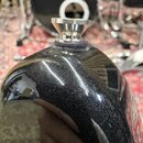 Detailní záběr na horní část černého, lesklého nástroje s metalickou texturou. Na vrcholu je umístěn chromovaný kovový prstenec s bílým plastovým kro…