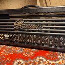 Černý kytarový kombozesilovač s logem Bugera v horní části. Na ovládacím panelu je nápis TRIBECO a text 100-WATTS 2-CHANNEL VALVE AMPLIFIER. Přístroj…