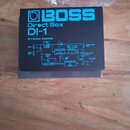 Fotografie znázorňuje černý papírový manuál nebo přehledový list. V horní části je modré logo BOSS a nápisy Direct Box DI-1. Pod nimi se nachází sché…