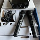 Sada bezdrátových mikrofonů v bílé krabici. Obsahuje černý přijímač s dvěma anténami a nápisy SR 40, PRO2, VOLUME a ON/OFF, dva černé ruční mikrofony…