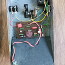 Fotografie zachycuje vnitřek kovového šasi s elektronickými komponenty. Uvnitř jsou umístěny tři potenciometry, deska plošných spojů s rezistory a ko…