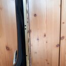 Detailní pohled na hmatník a krk černé elektrické kytary. Je vidět černý lakovaný povrch, hmatník s bílými polohovými značkami a kovové struny. Nástr…
