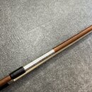 Detailní pohled na část dřevěného nástroje nebo příslušenství hnědé barvy. Mezi dvěma dřevěnými sekcemi je umístěn stříbrný kovový prstenec s jemným…