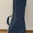 Modrý poloměký pouzdro na hudební nástroj z textilie s vzhledem připomínajícím denim. Má hnědé kožené nebo syntetické prvky v horní části a na spodní…