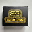 Černá čtvercová krabice s žlutým potiskem. Uprostřed je logo MXR v obdélníku s nápisem CUSTOM SHOP a pod ním text THIRD MAN HARDWARE. Celý grafický p…