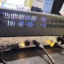 Zadní strana černého kytarového komba s ventilační mřížkou v horní části. Na panelu jsou nápisy Hughes & Kettner, MIDI IN, FOOTSWITCHES (Channels, Ef…