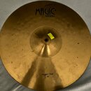 Kulatý mosazný činel zlaté barvy s viditelným kovánívým povrchem. V horní části je černý nápis Magic BRASS a v dolní části text HI-HAT TOP 14". U stř…