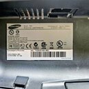 Fotografie detailně zobrazuje typový štítek na černém plastovém povrchu. Štítek obsahuje značku SAMSUNG a model T220 s kódovými označením LS22TWHSUV/…