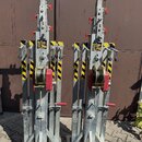 Na fotografii jsou dva identické kovové vozíky s mechanismem navijáku a červenými páky. Konstrukce je z galvanizované oceli s žluto-černými varovnými…