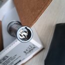 Detailní pohled na konektor mikrofonu typu XLR s třemi zlatými piny. Konektor je vyroben z matřitého kovu a vykazuje mírné známky opotřebení v podobě…