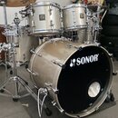 Sada bubnů značky SONOR v béžové barvě s kovovým kováním. Na předním koži basového bubnu je bílý nápis SONOR s logem. Sestava obsahuje basový buben,…
