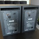 Dva černé studiové monitory z pohledu zezadu. Na zadním panelu obou přístrojů je nápis Active Studio Loudspeaker SC 207, logo EVE Audio GmbH a web ww…