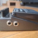 Černý efekt pedál s kovovým šasi a třemi ovládacími knoflíky. Na horní části je nápis Reverb a další texty, které jsou z tohoto úhlu částečně zakryty…