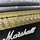 Detailní pohled na ovládací panel kytarového komba značky Marshall. Zlatý kovový panel nese nápis JMD:1 a 50 Watt Valve Powered. Jsou zde vidět čtyři…