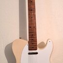 Elektrická kytara typu Telecaster s přírodním dřevěným povrchem těla a hmatníkem. Má bílý pickguard, jeden krkový snímač a jeden mostový snímač v kov…